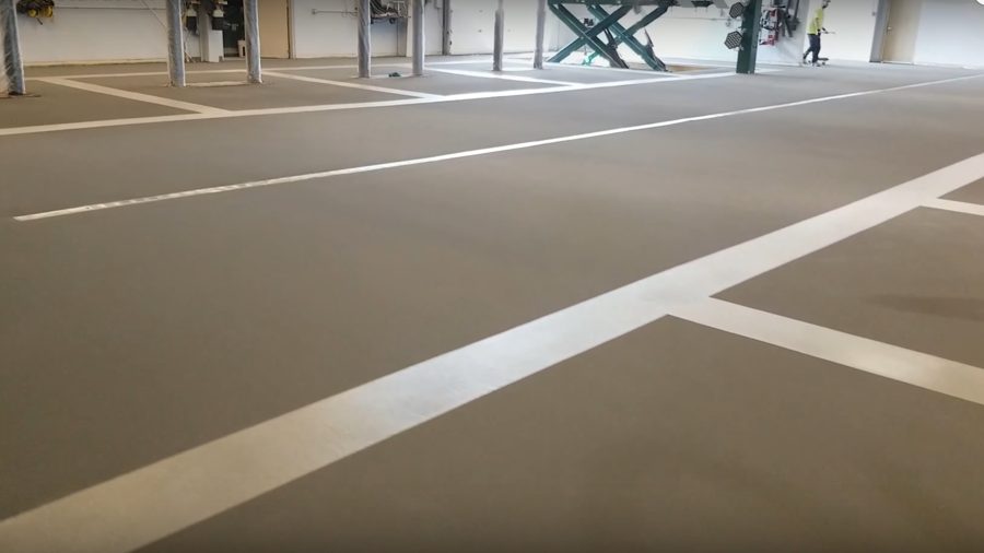 Dealership service bay with striped resinous floor and vehicle lifts