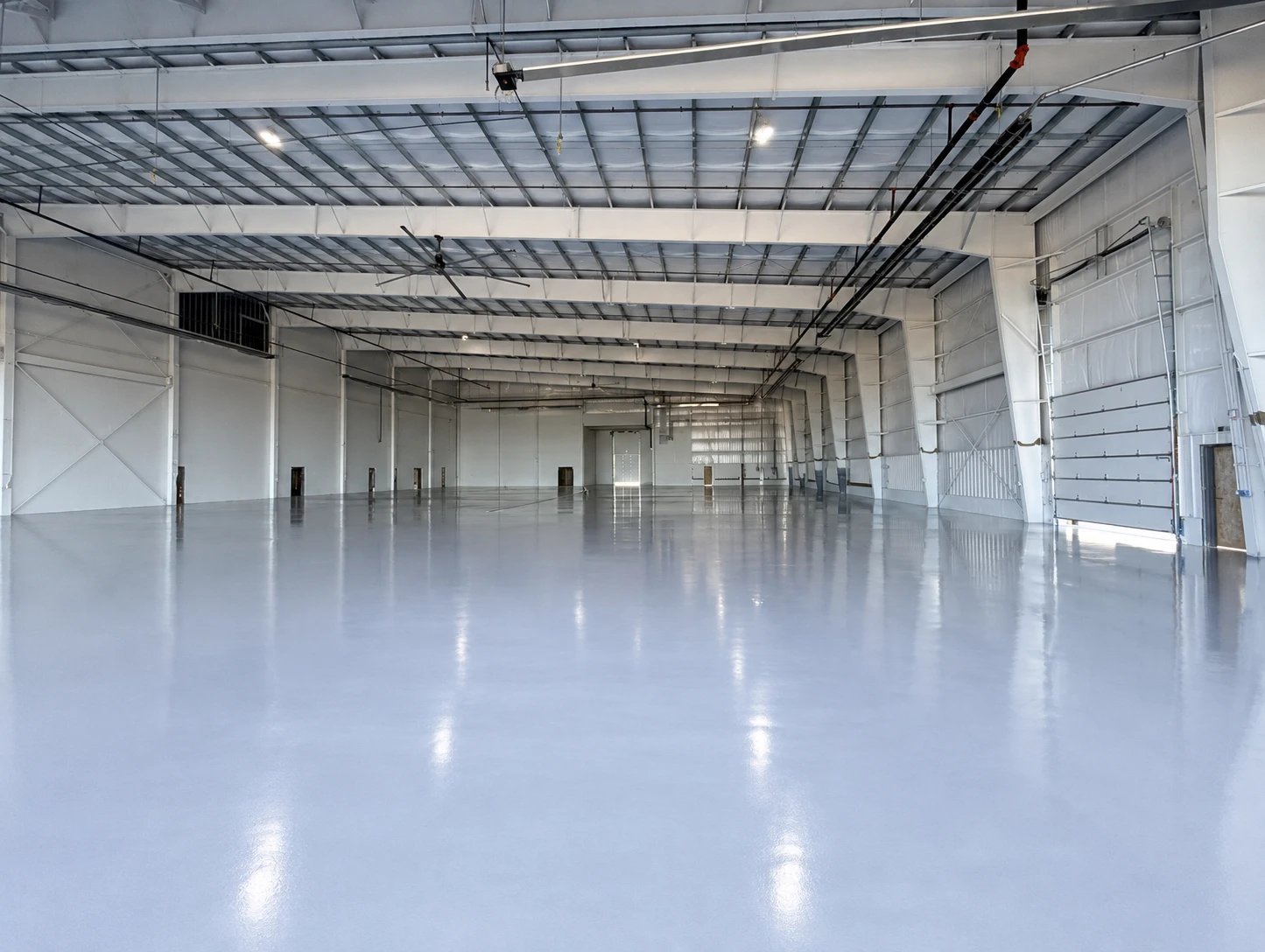 Aircraft hangar with a seamless light-gray resinous floor, completed October 2026