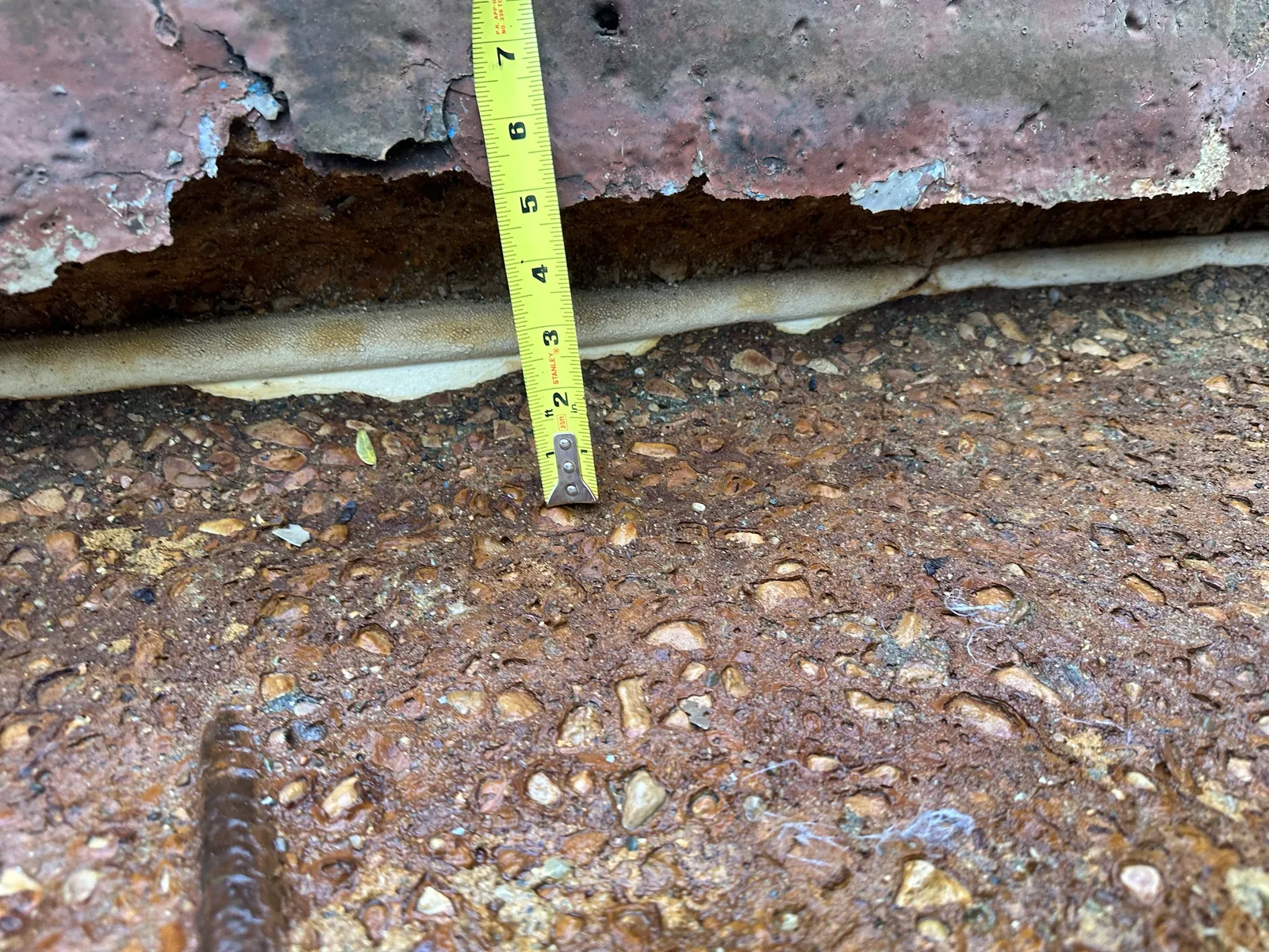 Containment curb with severe section loss and exposed rebar before rebuilding