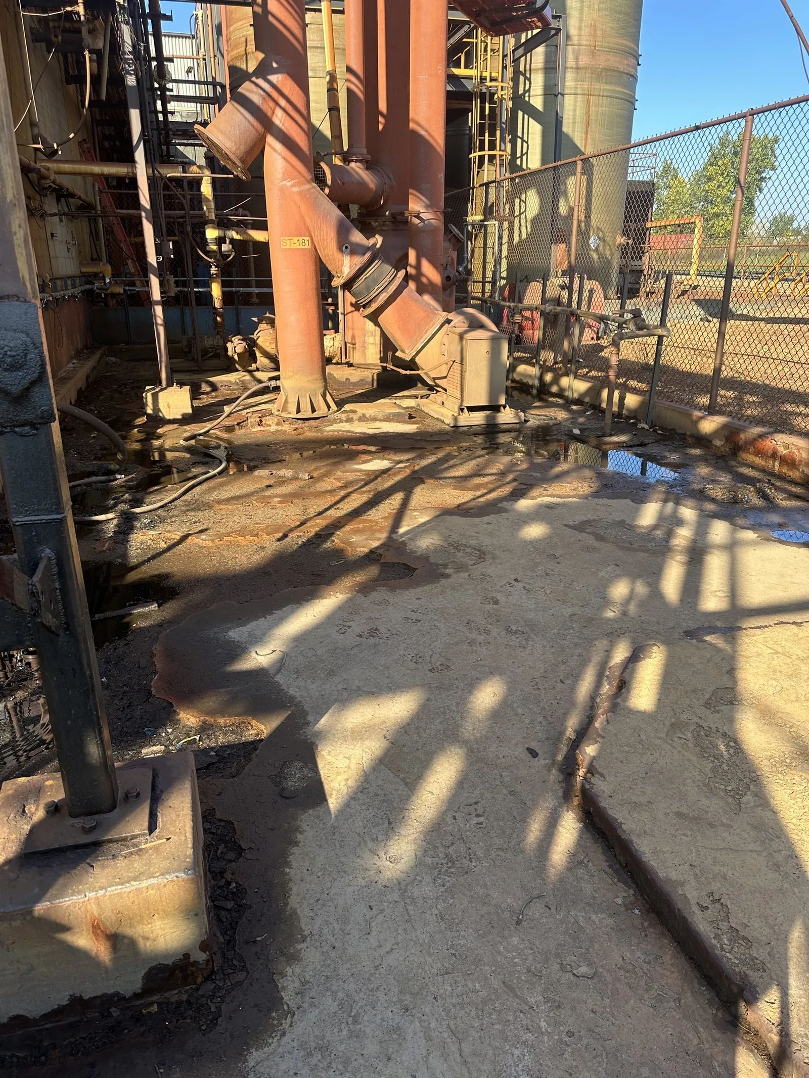 Secondary containment pad before repair, with etched concrete and failed slope at a chemical processing facility