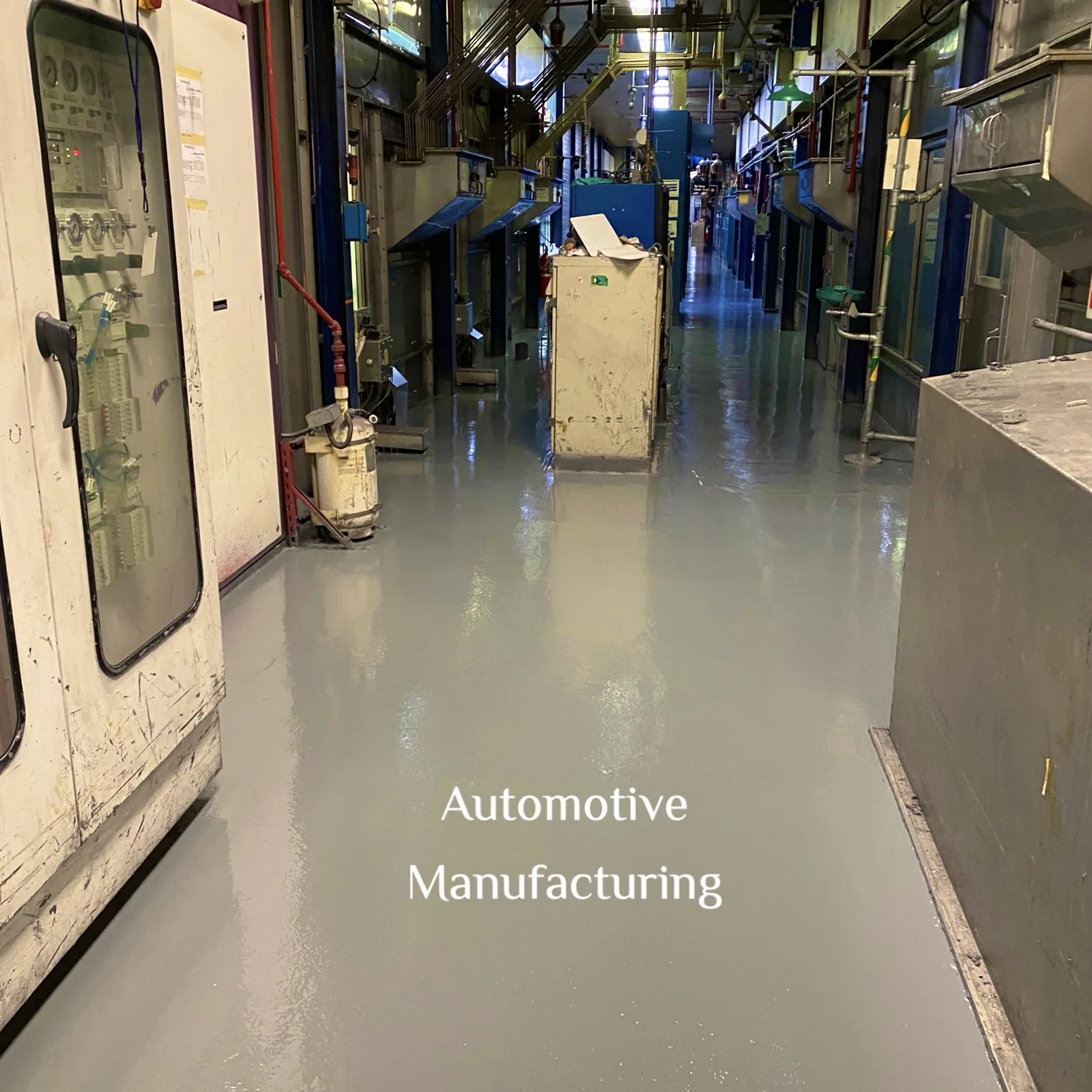 Grey seamless floor along an automotive manufacturing aisle between process equipment